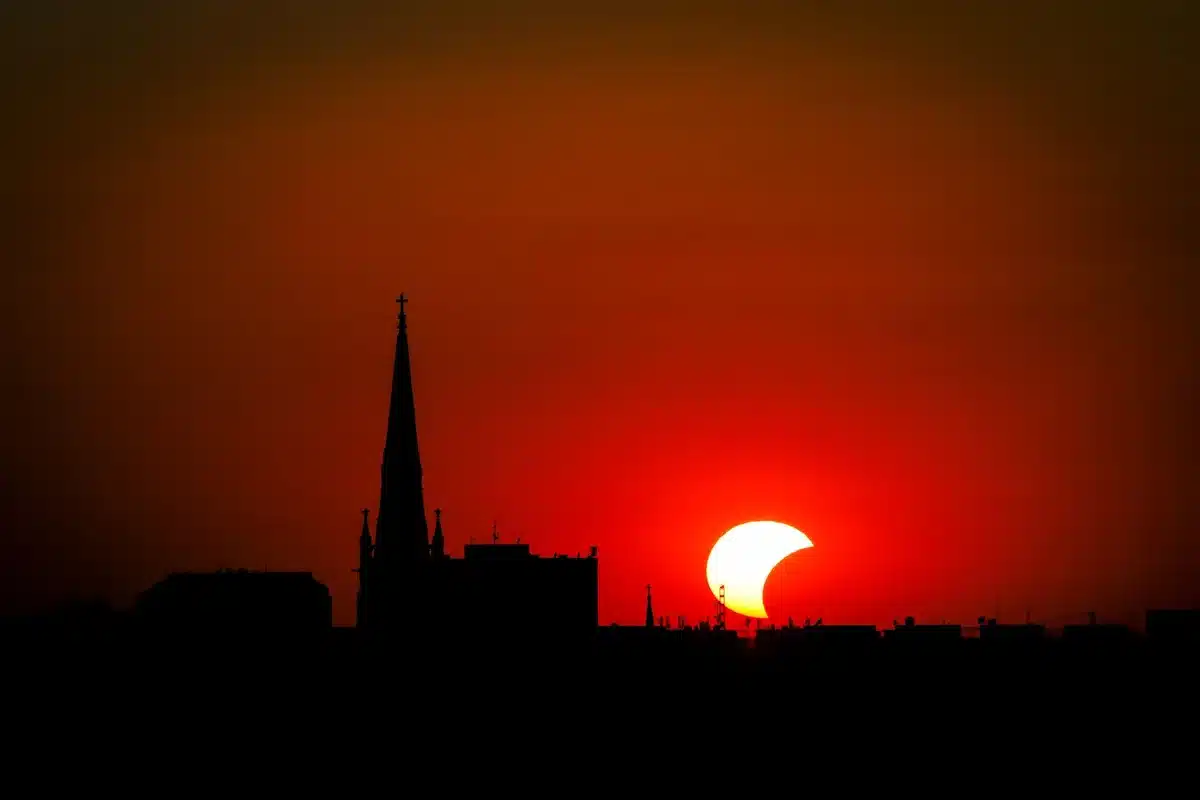 Cielo notturno durante un'eclissi solare con sagome di città sullo sfondo