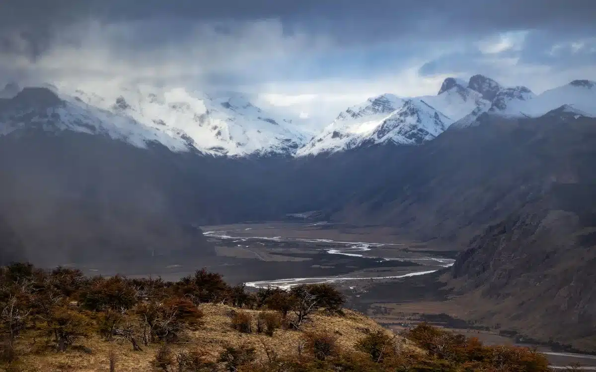 Paesaggio remoto della Patagonia con montagne, pianure e fiume sotto cielo aperto