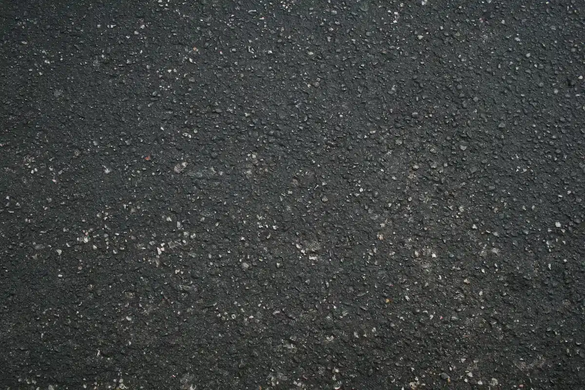 Piccolo frammento osseo fossile tra depositi di sedimento e rocce scure, illuminato per mostrare i dettagli anatomici