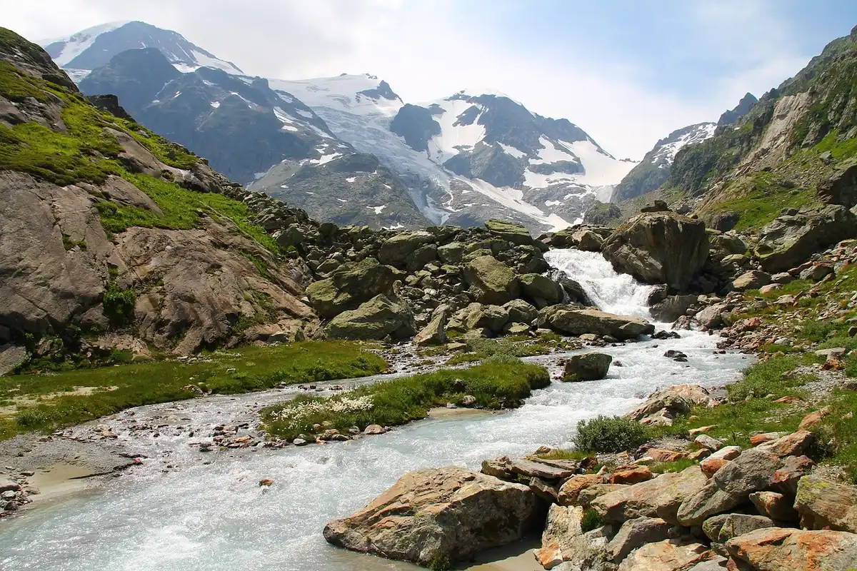 Fiume di montagna in piena con detriti e fango che scorre attraverso una valle himalayiana