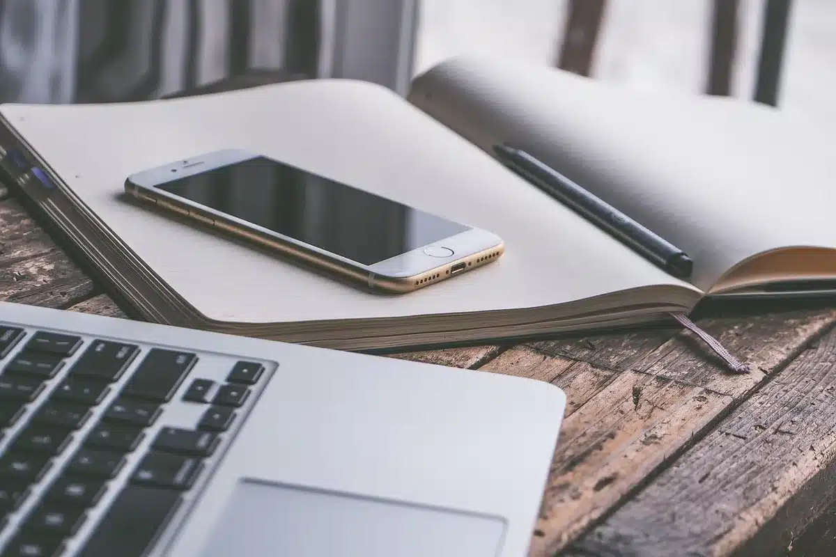 Mani che tengono uno smartphone con interfaccia di notizie, cuffie e tazza su scrivania