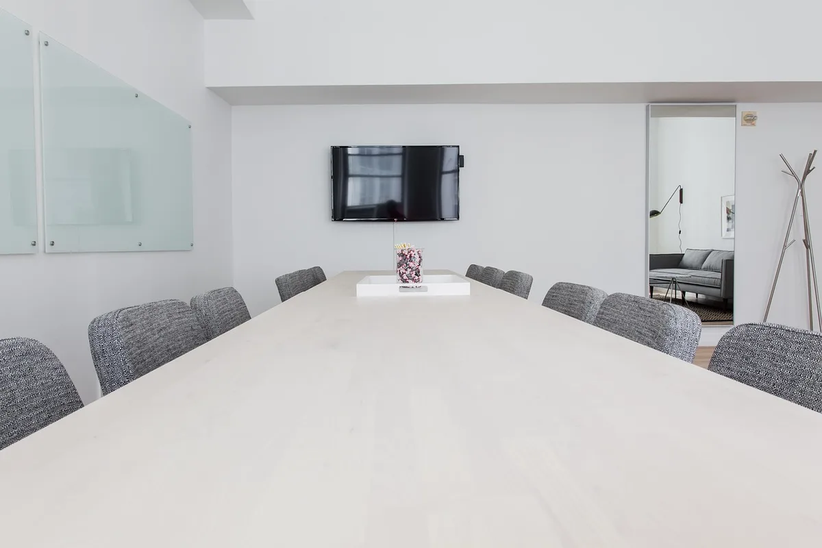 Sala riunioni con mani su tavolo e documenti che segnalano una pausa nei lavori sull'IA