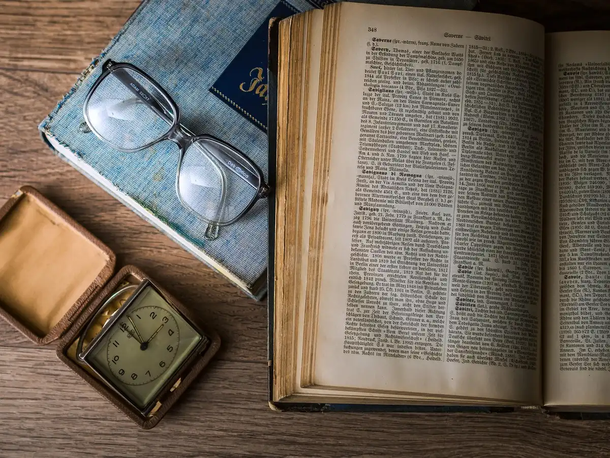 Zaini e libri di lingua su una panchina di cortile scolastico, mani anonime indicano un mappamondo