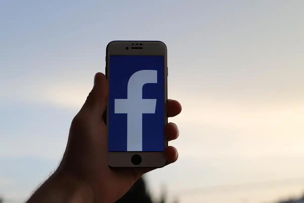Mani che tengono un ciak e uno smartphone con icone social su un tetto urbano