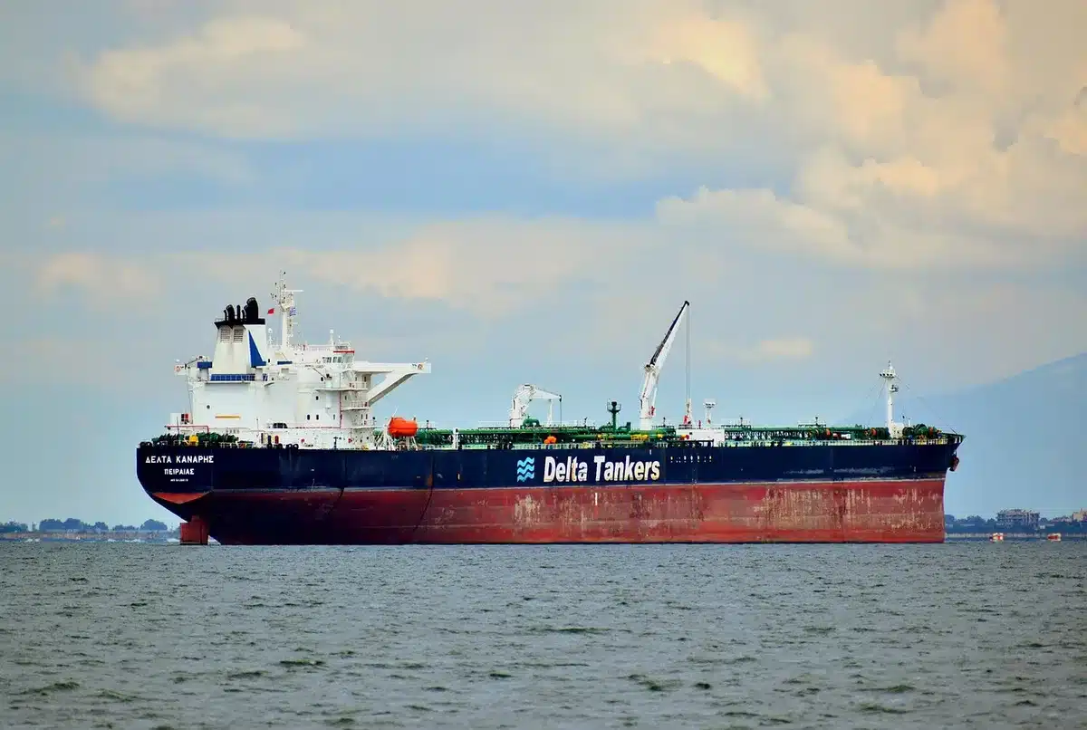 Silhouette di una banchina portuale e gru che evocano l'arrivo di una grande petroliera