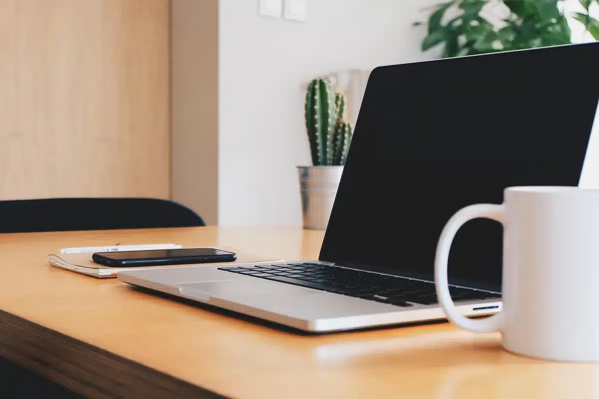 Mani anonime che tengono un libro su un tavolo da caffè con laptop sfocato