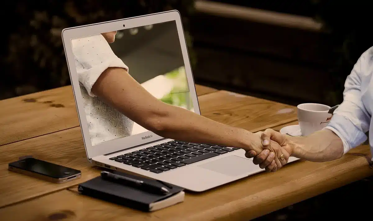Mani anonime su laptop con icone cloud e documenti che rappresentano agenti che lavorano in background