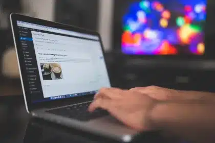 Mani anonime che digitano su un portatile con schizzi di flusso su un taccuino accanto