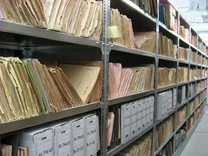 Pila di pergamene antiche sul tavolo di un archivio con guanti da laboratorio