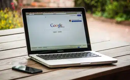 Mani che tengono uno smartphone sopra un tavolo con caffè e occhiali