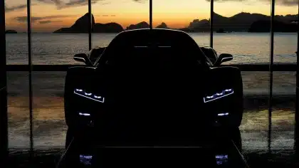 Vettura sportiva futuristica con ali retrattili davanti a un hangar, vista laterale anonima